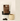 A white stand-up pouch of 8NOIR ULTRA hot chocolate with a large brown label, shown next to a cream ceramic mug filled with hot chocolate and a few dark chocolate pieces on a light surface.