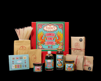 A curated gift set of Poon's Chinese Fine Goods arranged on a white surface against a solid red background. The set includes a large red gift box with a colorful teal and gold label, a pack of uncooked noodles, two brown kraft paper pouches, a small blue tea box, a bottle of soy sauce, a bottle of hot sauce, and two small jars with wrapped contents.