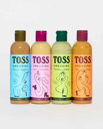 Four bottles of Toss dressing in different flavors on a white background