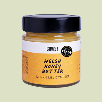 Jar of Welsh Honey Butter with a black lid on a light green background
