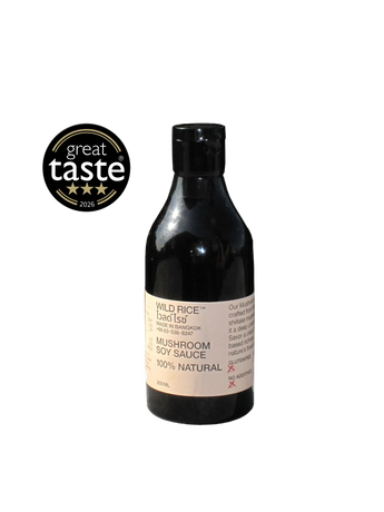 A bottle of Wild Rice Mushroom Soy Sauce on a light gray background, featuring a black bottle with a beige label and a 'great taste' rating badge on the left.