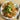 Plated dish of shrimp and noodles garnished with herbs and a lime wedge on a wooden table.
