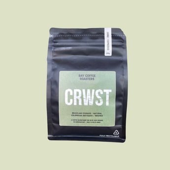 A black stand-up coffee bag with a large light green label reading 'CRWST' and 'Bay Coffee Roasters' on a pale yellow-green background.