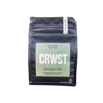 A black stand-up coffee bag with a large light green label reading 'CRWST' and 'Bay Coffee Roasters' on a pale yellow-green background.