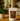 A stand-up pouch of Bonoir Ultra Hot Chocolate sits on a wooden table in a warm, softly blurred kitchen setting. The pouch is off-white with a large brown label featuring the brand name and product text, with a cocoa pod illustration.