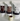 Three white bags of Sonoir Ultra Hot Chocolate chocolate mix arranged on a white surface, with a small speckled cream mug filled with hot chocolate in front of them.