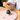 Person using a wooden tea whisk over a green teapot on a pink coaster.