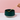 Green ceramic bowl with a hand holding a yellow spoon against a pink background