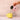 Person pouring coffee from a pink mug into a yellow mug on a beige background