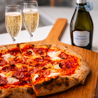 Artisan pepperoni pizza with bubbling mozzarella and crispy pepperoni, paired with two glasses of Italian prosecco for a perfect date night meal kit.