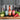 Three bottles of Tashin sauce on a wooden cutting board with vegetables in a kitchen setting.