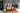 Three bottles of Tashin sauce on a wooden cutting board with vegetables in a kitchen setting.