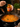 Person adding curry masala paste to a pan of food with a jar of curry masala paste in the background.