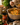 Person ladling curry into a bowl with curry masala paste jar on a stove