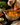 Person adding curry masala paste to a pot of food on a stove with a jar of curry masala paste in hand.