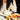 Person eating noodles with a bowl of soup and a plate of rice on a table.