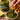 Person dipping a piece of fried food into Atrangi Minit & Coriander Chutney with a jar of chutney and lime in the background.