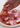 Hand placing prosciutto onto a pizza with tomato sauce and mozzarella cheese.