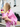A woman in a pink blazer holding two bottles of Toss Dress Shampoo from behind, showcasing the pink and yellow packaging on a city street.