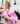 A woman in a pink jacket holds two bottles of Toss Dressing in her hands, photographed from behind on a city street.