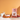 A bag of CRWST Gel and Raspberry Granola Australia stands on a white table against a warm orange background, styled with a bowl of granola, berries, a mug, and jars in a bright, clean kitchen scene.