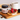 A jar of Crust Chocolate Caramel Spread is shown on a wooden board next to toast topped with caramel spread, raspberries, and blackberries, with a mug of coffee in the background.