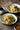 Two bowls of noodles with vegetables on a wooden table