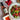 Bowl of salad with raspberries, a bottle of strawberry and mint vinegar, and a small dish of dressing on a light surface.
