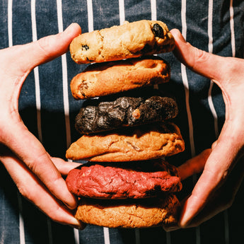 Hands holding a stack of colorful cookies against a striped background