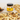 Jar of Welsh Honey Butter with bread slices topped with seeds on a light background