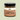 Jar of chocolate caramel spread with a black lid on a light green background