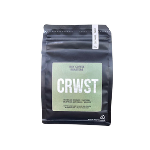A black stand-up coffee bag with a large light green label reading 'CRWST' and 'Bay Coffee Roasters' on a pale yellow-green background.