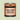 A cylindrical metal can of CRWST Chai Spiced Milk Hot Chocolate, featuring a terracotta-colored label with black text and stripes, set against a solid pale sage green background.