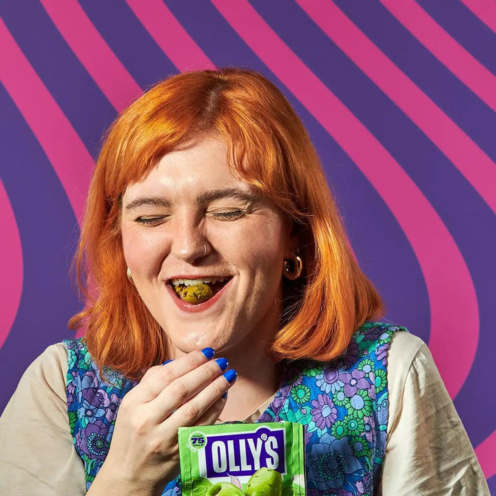 Olly's garlic and basil green olives being eaten by a smiling woman